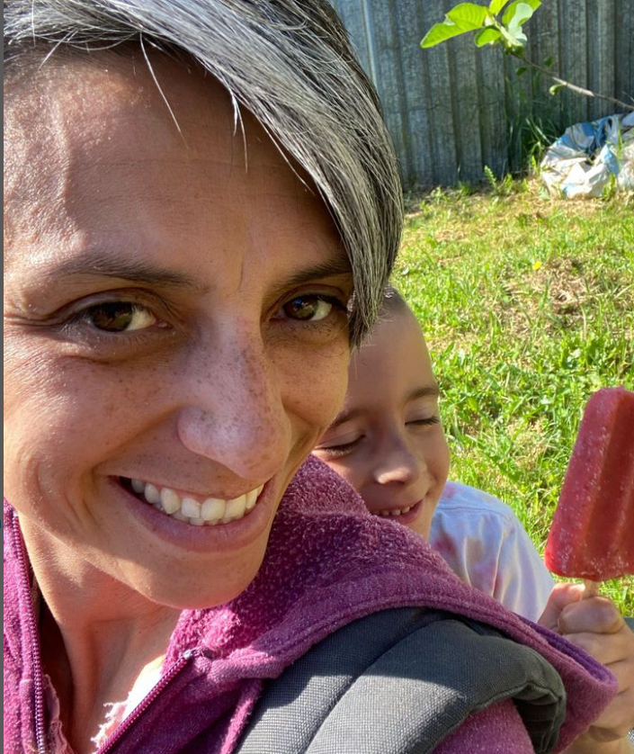 Liana and her child in a backyard, smiling, eating a popsicle.